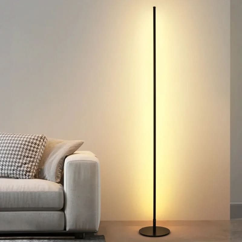 Slim metal LED floor lamp beside a reading chair - product photo 1