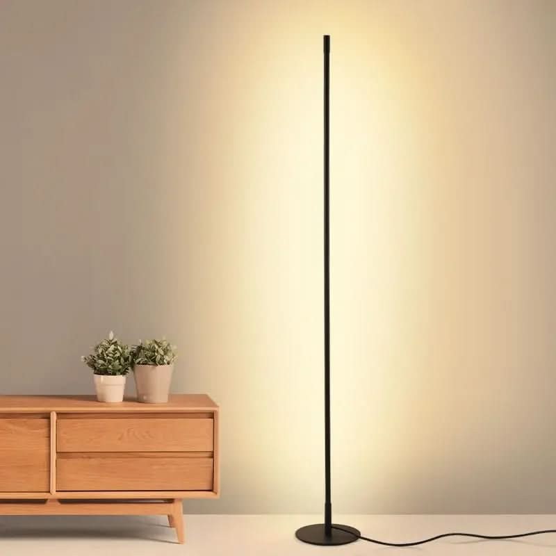 Slim metal LED floor lamp beside a reading chair - product photo 3