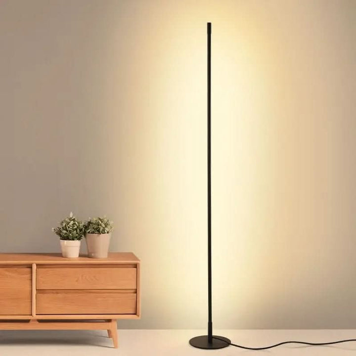 Slim metal LED floor lamp beside a reading chair - product photo 3