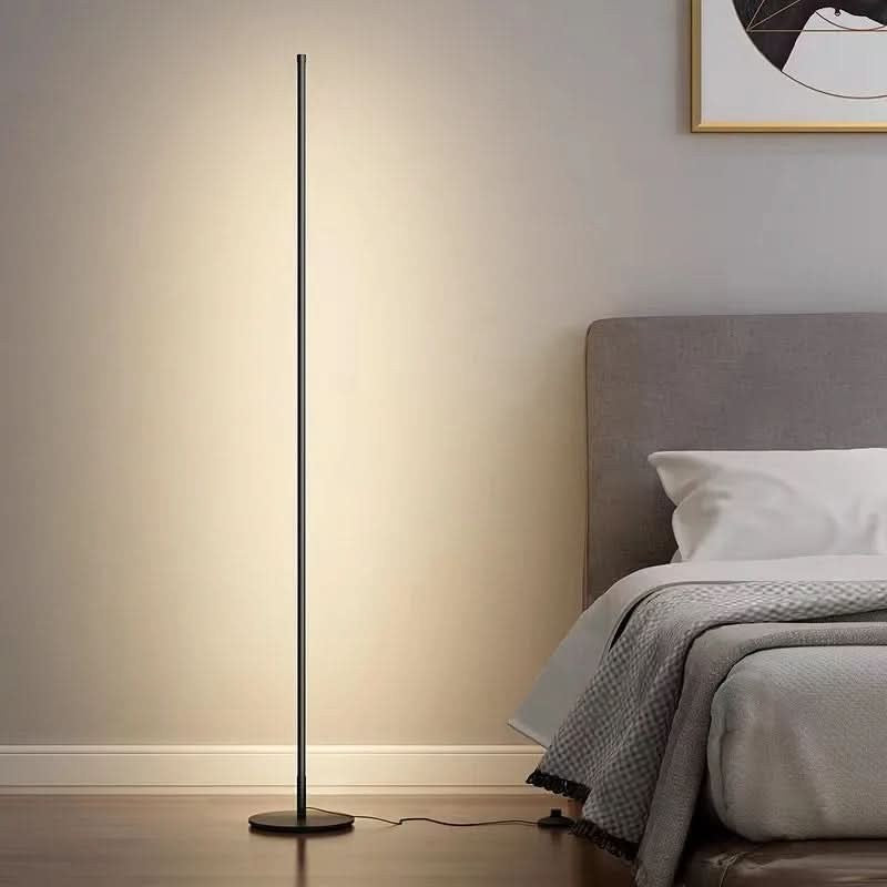Slim metal LED floor lamp beside a reading chair - product photo 4