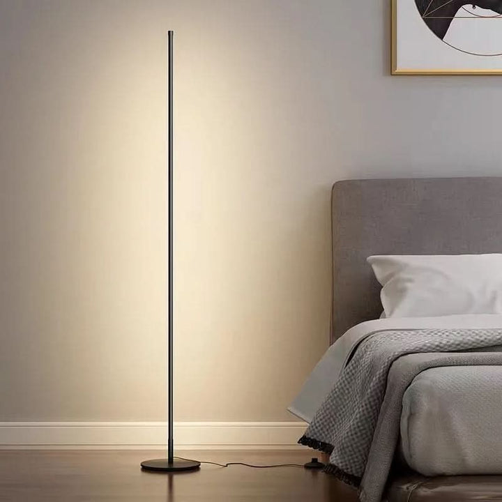 Slim metal LED floor lamp beside a reading chair - product photo 4