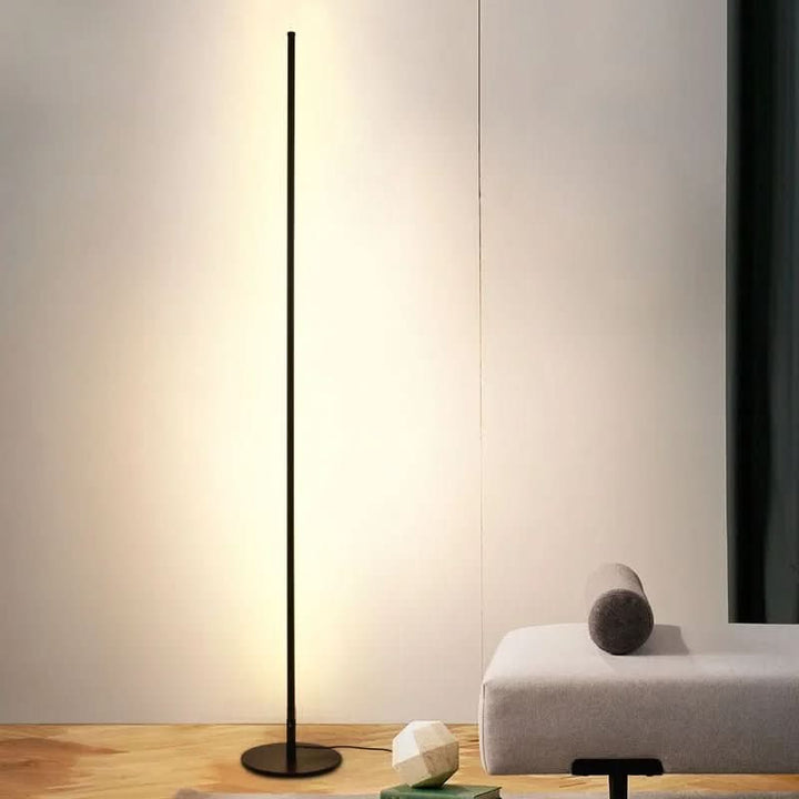 Slim metal LED floor lamp beside a reading chair - product photo 5
