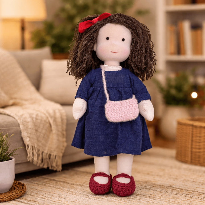 Handmade Waldorf-style cotton doll with brown curls and a red bow, a navy dress and a pink handbag