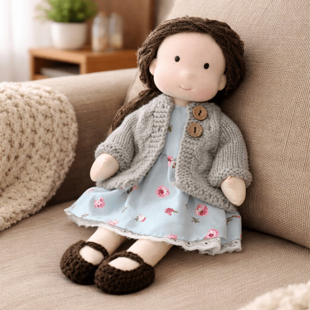Handmade Waldorf-style cotton doll with brown hair, a gray cardigan and a blue floral dress