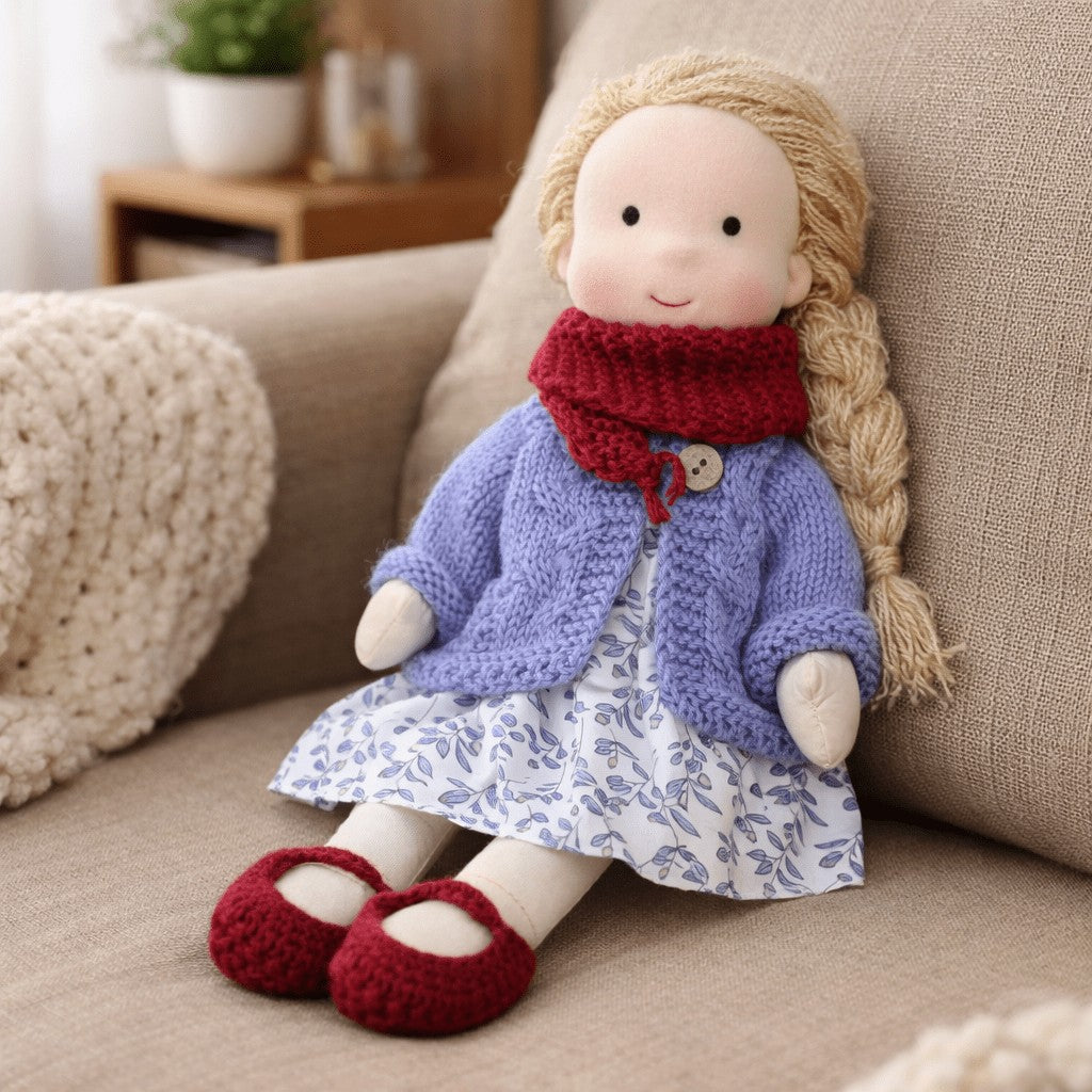 Handmade Waldorf-style cotton doll with a long blonde braid, a purple cardigan, floral skirt and red shoes