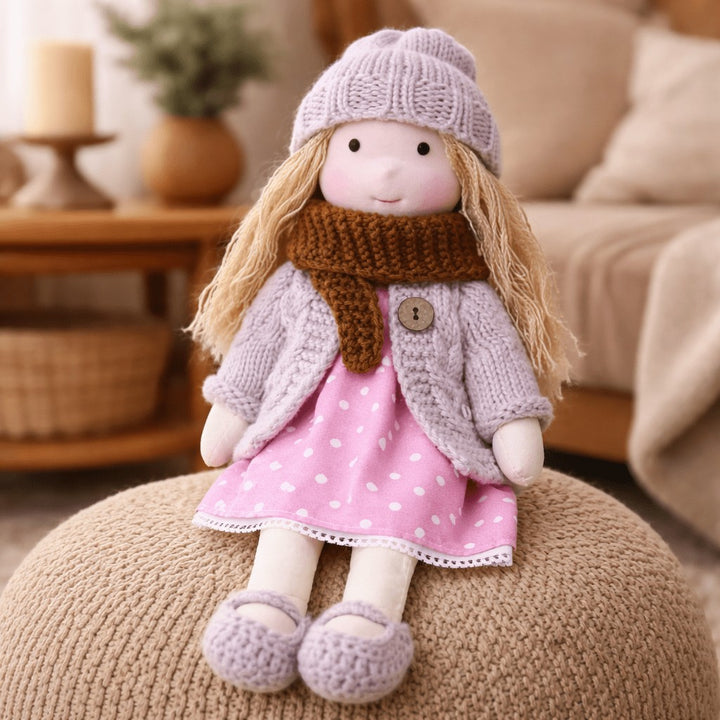 Handmade Waldorf-style cotton doll with a lilac knit hat, brown scarf and a pink polka-dot dress