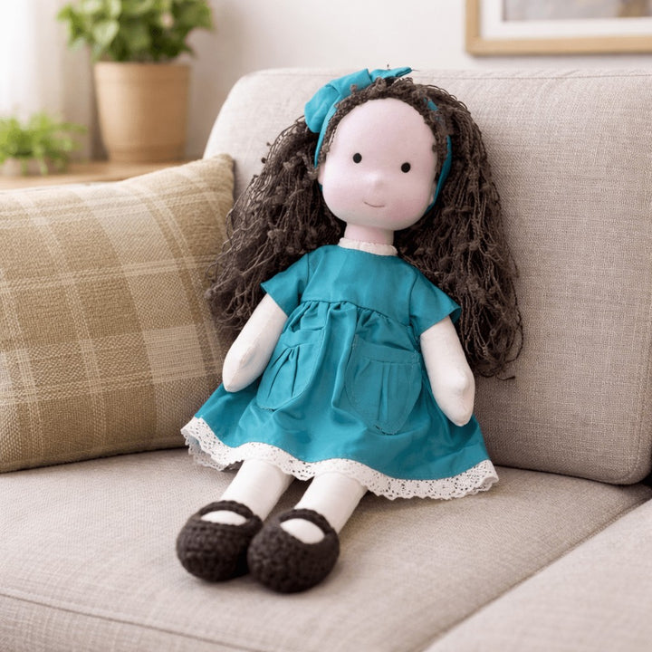 Handmade Waldorf-style cotton doll with dark curly hair, a teal dress and a matching teal hair bow