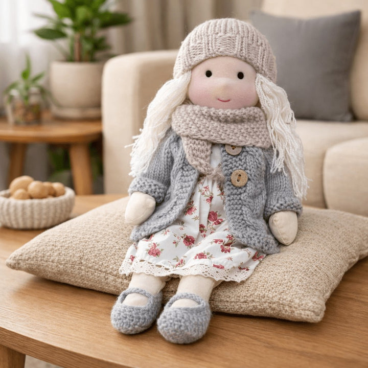 Handmade Waldorf-style cotton doll with a cream knit hat, gray cardigan and a red floral skirt