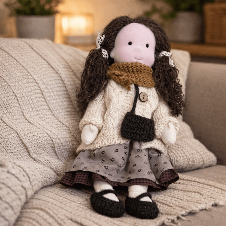 Handmade Waldorf-style cotton doll with dark curly hair, a brown scarf, cream cardigan and a shoulder bag