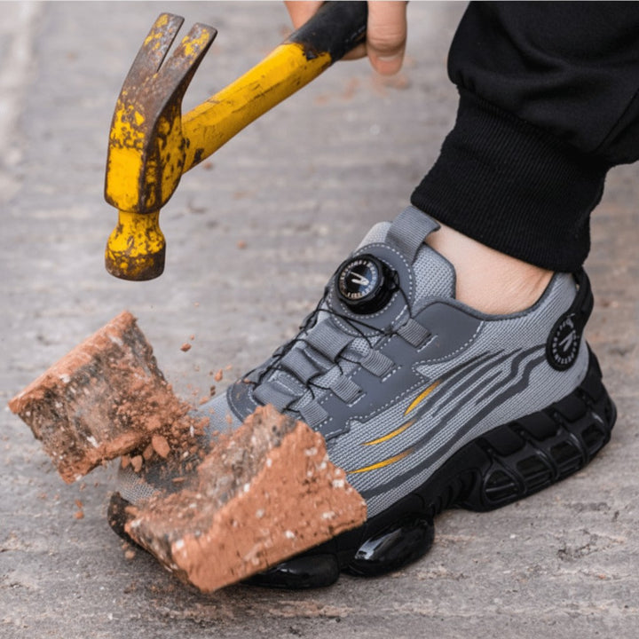 Hammer striking a brick resting on the reinforced toe cap of a gray work sneaker